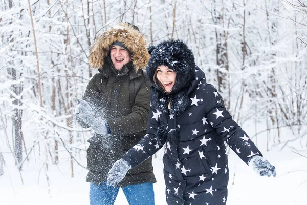 Amor, relacionamento, estação e conceito de amizade - homem e mulher se divertindo e brincando com a neve na floresta de inverno — Fotografia de Stock