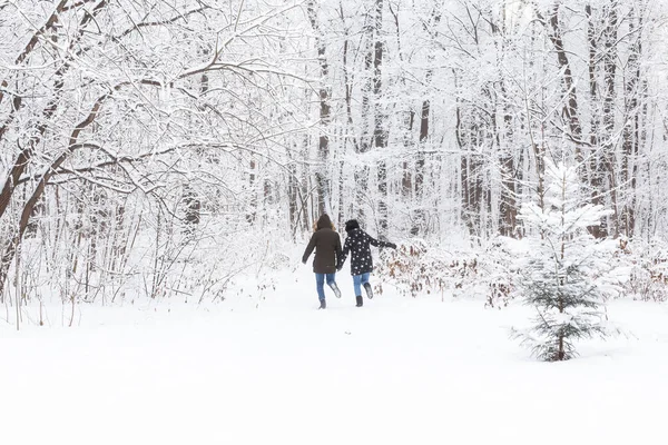 Un jeune et beau couple s'amuse dans le parc enneigé, courant et se tenant la main. Concept de Saint-Valentin. Saison d'hiver. — Photo