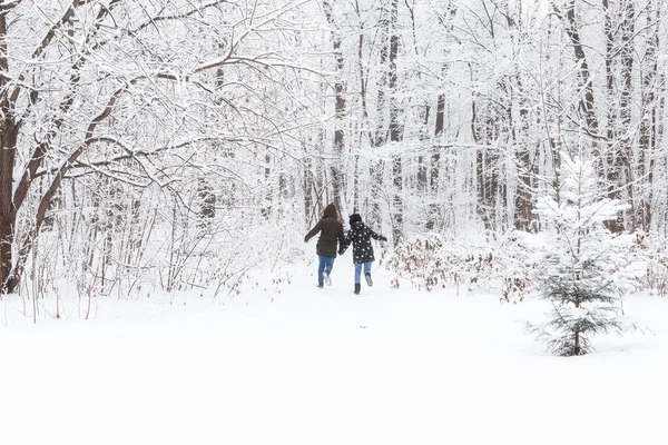 Un jeune et beau couple s'amuse dans le parc enneigé, courant et se tenant la main. Concept de Saint-Valentin. Saison d'hiver. — Photo