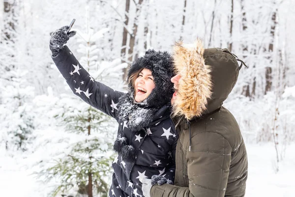 Concept de saison et de relation - Couple drôle prenant selfie en hiver — Photo