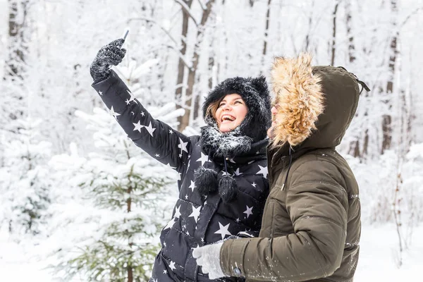 Technologies et concept de relation - Couple souriant heureux prenant un selfie dans une forêt d'hiver à l'extérieur — Photo