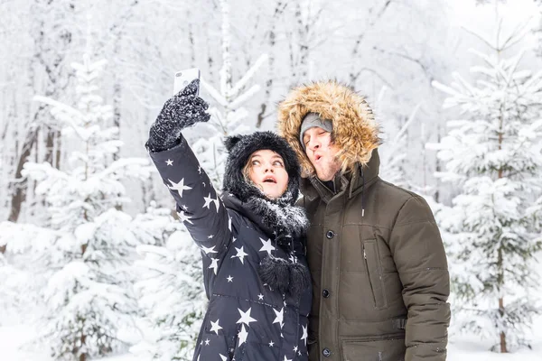 Temporada, amor, tecnologia e conceito de lazer - casal feliz tomando selfie por smartphone sobre fundo de inverno — Fotografia de Stock