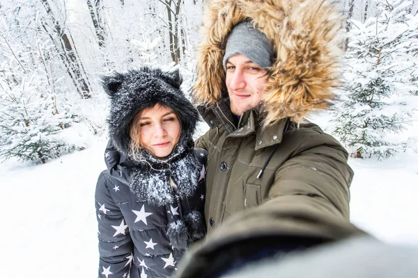 Sezon, miłość, technologia i wypoczynek koncepcja - szczęśliwa para robi selfie przez smartfona na tle zimy — Zdjęcie stockowe