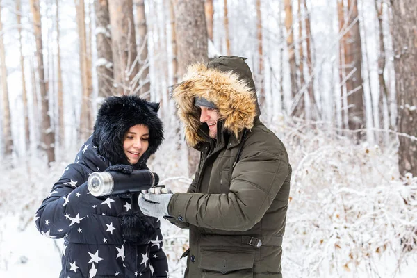 Jeune couple amoureux boire une boisson chaude d'un thermos et profiter de la nature hivernale. — Photo