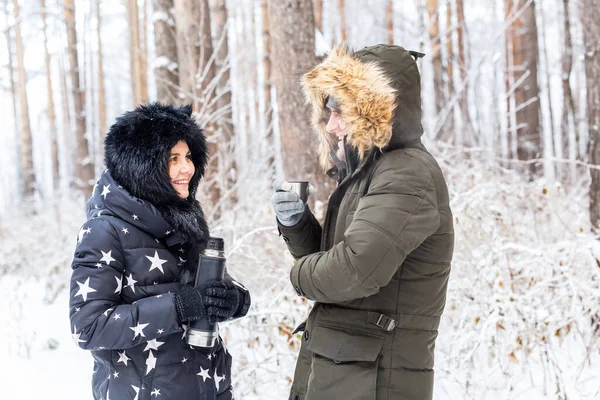 Conceito de temporada e caminhada - casal feliz bebendo chá quente na floresta de inverno — Fotografia de Stock