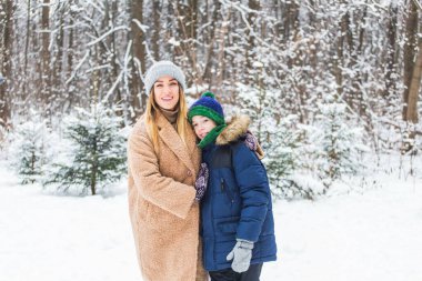 Kışın açık havada oğluyla mutlu anne portresi. Karlı park. Tek ebeveyn.