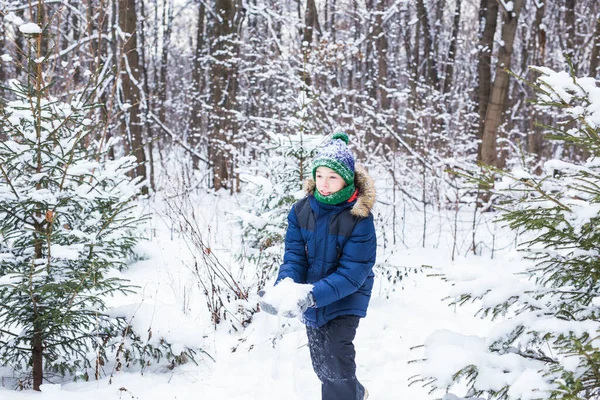 Mignon jeune garçon joue avec la neige, amusez-vous, sourit. Adolescent dans le parc d'hiver. Style de vie actif, activité hivernale, jeux d'hiver en plein air, boules de neige. — Photo