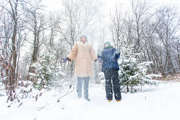 Parenting, fun et concept de saison - Bonne mère et son fils s'amusent et jouent avec la neige dans la forêt d'hiver — Photo