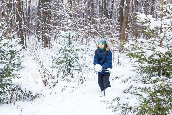 Rapaz bonito brinca com neve, diverte-te, sorri. Adolescente no parque de inverno. Estilo de vida ativo, atividade de inverno, jogos de inverno ao ar livre, bolas de neve. — Fotografia de Stock