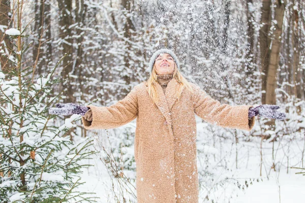 Young woman throwing snow in the air at sunny winter day, she is happy and fun.