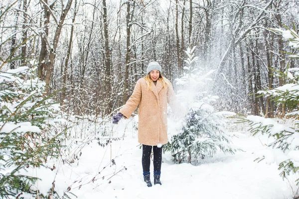 Jeune femme jetant de la neige dans les airs lors d'une journée ensoleillée d'hiver, elle est heureuse et amusante. — Photo