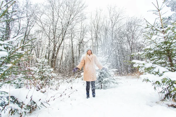 Jovem mulher jogando neve no ar no dia ensolarado de inverno, ela é feliz e divertida. — Fotografia de Stock