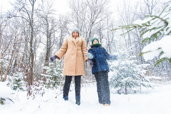 Rodzicielstwo, zabawa i koncepcja sezonu - szczęśliwa matka i syn bawią się i bawią się śniegiem w zimowym lesie — Zdjęcie stockowe