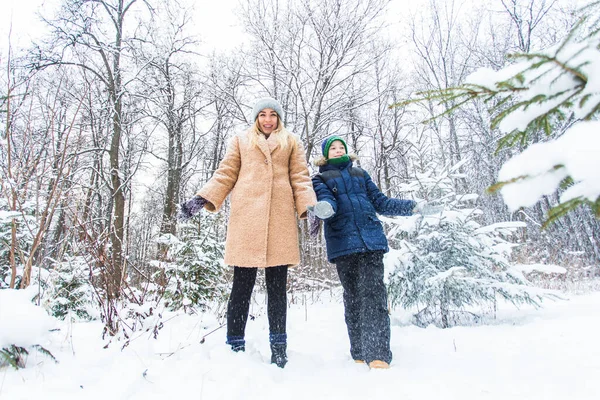 Crianza, diversión y concepto de temporada: madre e hijo felices divirtiéndose y jugando con la nieve en el bosque invernal — Foto de Stock