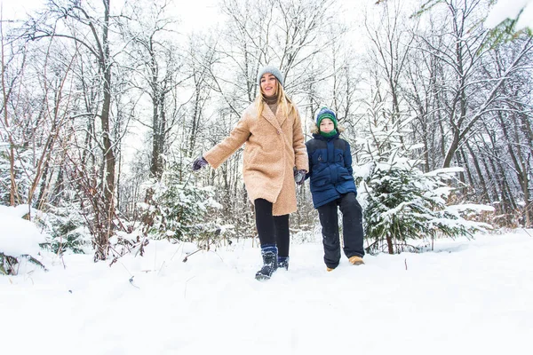 Parenting, fun et concept de saison - Bonne mère et son fils s'amusent et jouent avec la neige dans la forêt d'hiver — Photo