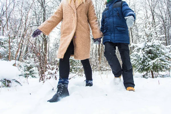 Crianza, diversión y concepto de temporada: madre e hijo felices divirtiéndose y jugando con la nieve en el bosque invernal — Foto de Stock