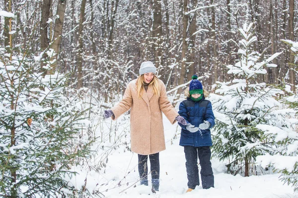 Веселье и сезон - Счастливая мать и сын веселятся и играют со снегом в зимнем лесу — стоковое фото