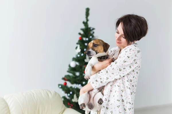 Joyeux jeune femme avec beau chien dans le salon avec arbre de Noël. Concept de vacances. — Photo