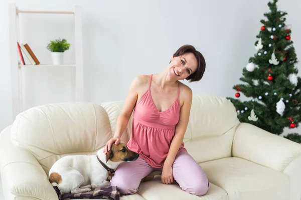 개를 키우는 행복 한 여성. 그 밑에는 크리스마스 트리가 있고. 장식 된 거실 — 스톡 사진