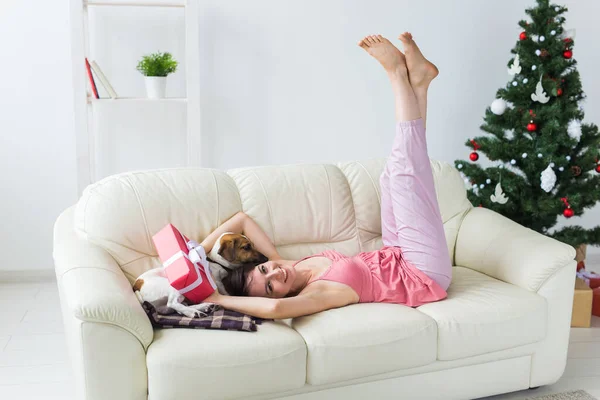 Ευτυχισμένη γυναίκα με σκύλο. Χριστουγεννιάτικο δέντρο με δώρα από κάτω. Διακοσμημένο σαλόνι — Φωτογραφία Αρχείου