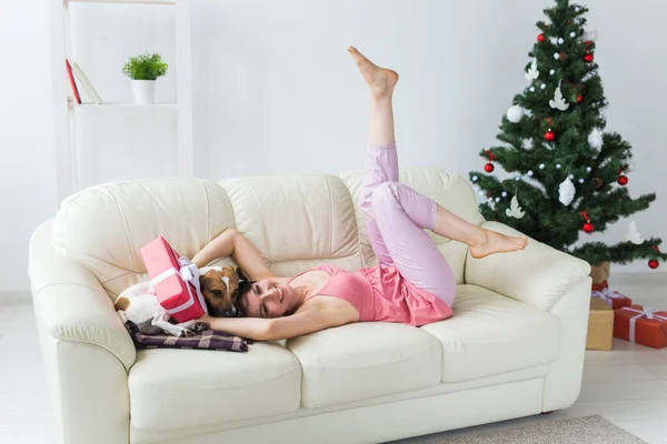 Oturma odasında Noel ağacı olan sevimli köpeği olan mutlu genç bir kadın. Tatil kavramı. — Stok fotoğraf