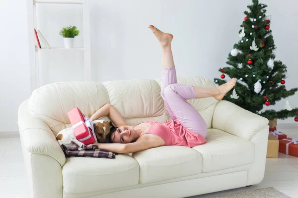 Oturma odasında Noel ağacı olan sevimli köpeği olan mutlu genç bir kadın. Tatil kavramı. — Stok fotoğraf