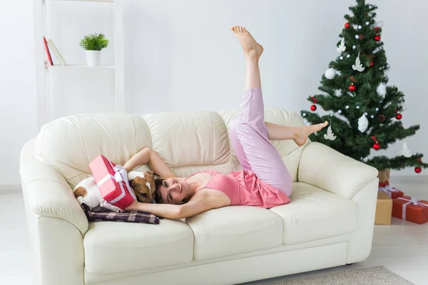 Femme heureuse avec chien. Arbre de Noël avec des cadeaux en dessous. Salon décoré — Photo