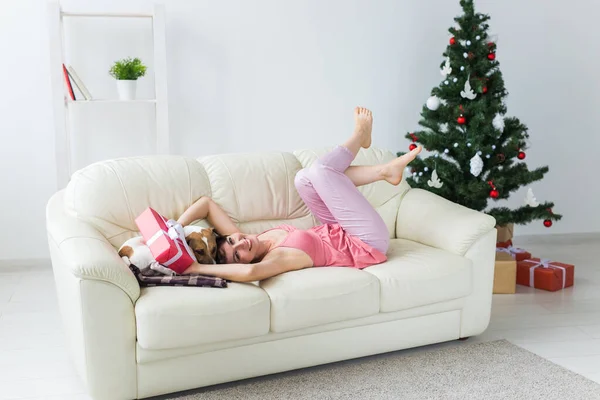 Šťastná mladá žena s krásným psem v obývacím pokoji s vánoční stromeček. Koncept dovolených. — Stock fotografie