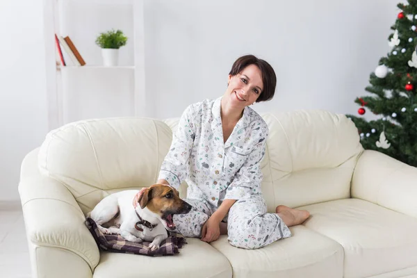 Happy young woman wearing pajama in living room with christmas tree. Holidays concept. — Stockfoto