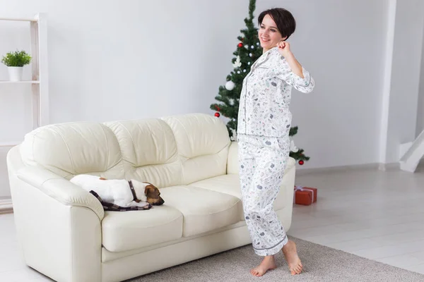 Gros plan de la femme portant un pyjama dans le salon avec un sapin de Noël. Concept de vacances. — Photo