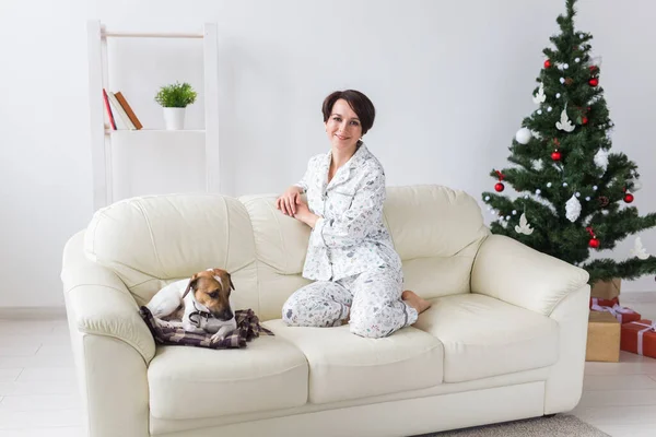 Šťastná mladá žena v pyžamu v obývacím pokoji s vánoční stromeček. Koncept dovolených. — Stock fotografie