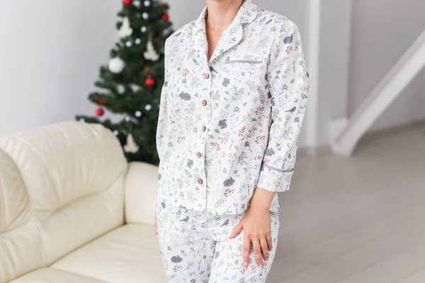 Primer plano de la mujer que usa pijama con perro encantador en la sala de estar con árbol de Navidad. Concepto de vacaciones. — Foto de Stock