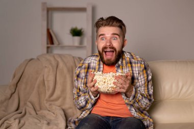 Sakallı adam film ya da spor oyunları seyrediyor. Geceleri evde patlamış mısır yiyor. Sinema, şampiyonluk ve hayran konsepti.