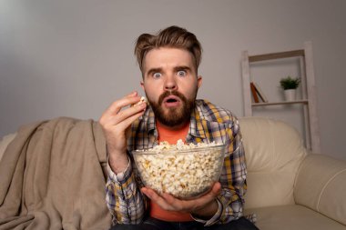 Sakallı adam film ya da spor oyunları seyrediyor. Geceleri evde patlamış mısır yiyor. Sinema, şampiyonluk ve hayran konsepti.