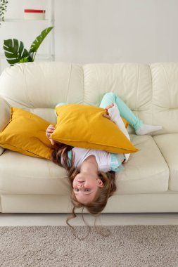 Kırık bileği ya da kolu olan bir çocuk gülümsüyor ve kanepede eğleniyor. Pozitif tutum, iyileşme ve çocuk konsepti.