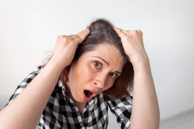 Dehşete düşmüş genç bir kadın aynaya bakıyor. Kafasındaki ilk gri saçlara ağzı açık bakıyor. Yaşlandığının ilk işareti..