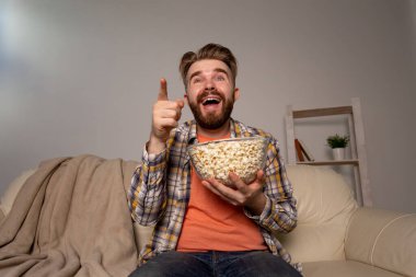 Sakallı adam film ya da spor oyunları seyrediyor. Geceleri evde patlamış mısır yiyor. Sinema, şampiyonluk ve eğlence konsepti.