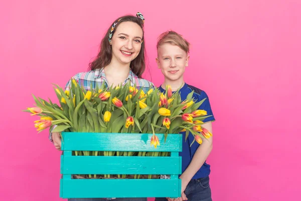 Family portrait sister and teenager brother with tulips on pink background — Stock Photo, Image