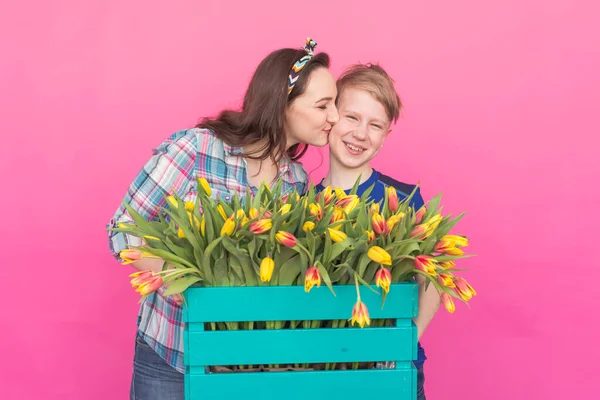 Family portrait sister and teenager brother with tulips on pink background — Stock Photo, Image