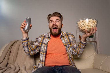 Sakallı adam film ya da spor oyunları seyrediyor. Geceleri evde patlamış mısır yiyor. Sinema, şampiyonluk ve hayran konsepti.