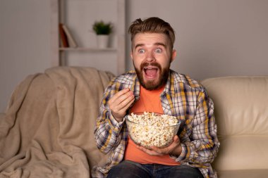 Sakallı adam film ya da spor oyunları seyrediyor. Geceleri evde patlamış mısır yiyor. Sinema, şampiyonluk ve hayran konsepti.