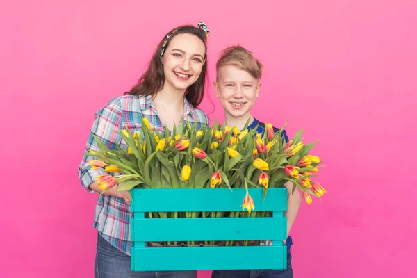 Family portrait sister and teenager brother with tulips on pink background — Stock Photo, Image