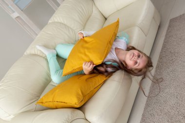 Kırık bileği ya da kolu olan bir çocuk gülümsüyor ve kanepede eğleniyor. Pozitif tutum, iyileşme ve çocuk konsepti.