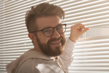 Sakallı genç adam penceredeki delikten bakar ve sokağa bakar. Gözetleme ve merak konsepti