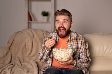 Sakallı adam film ya da spor oyunları seyrediyor. Geceleri evde patlamış mısır yiyor. Sinema, şampiyonluk ve hayran konsepti.