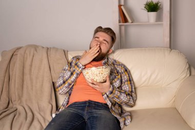 Sakallı adam film ya da spor oyunları seyrediyor. Geceleri evde patlamış mısır yiyor. Sinema, şampiyonluk ve hayran konsepti.