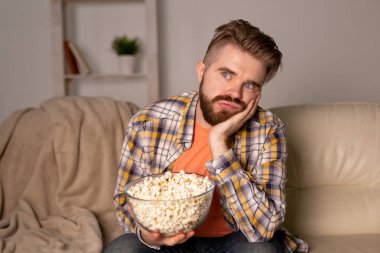 Kanepede televizyon izleyen bekar bir adam.