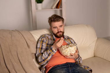 Kanepede televizyon izleyen bekar bir adam.