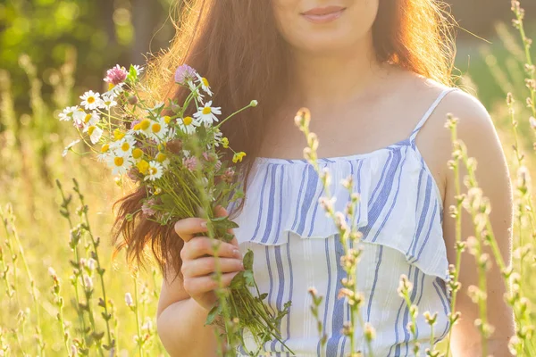 Großaufnahme einer Frau mit Wildblumen an einem sonnigen Sommertag. Konzept der Freude an der Kommunikation mit der sommerlichen Natur — Stockfoto