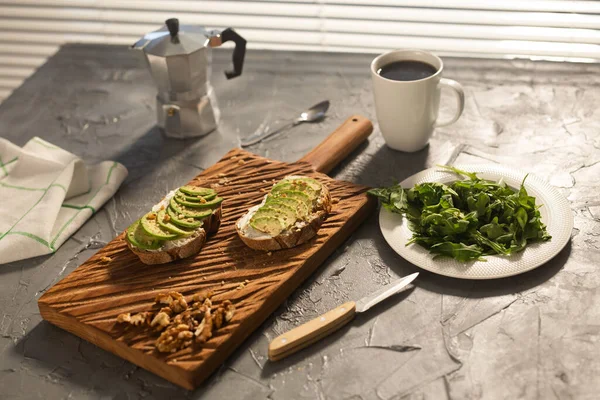 Avocat tranché sur pain grillé aux noix et au café. Épinards sur une assiette et moka pot. Petit déjeuner et concept d'alimentation saine. — Photo